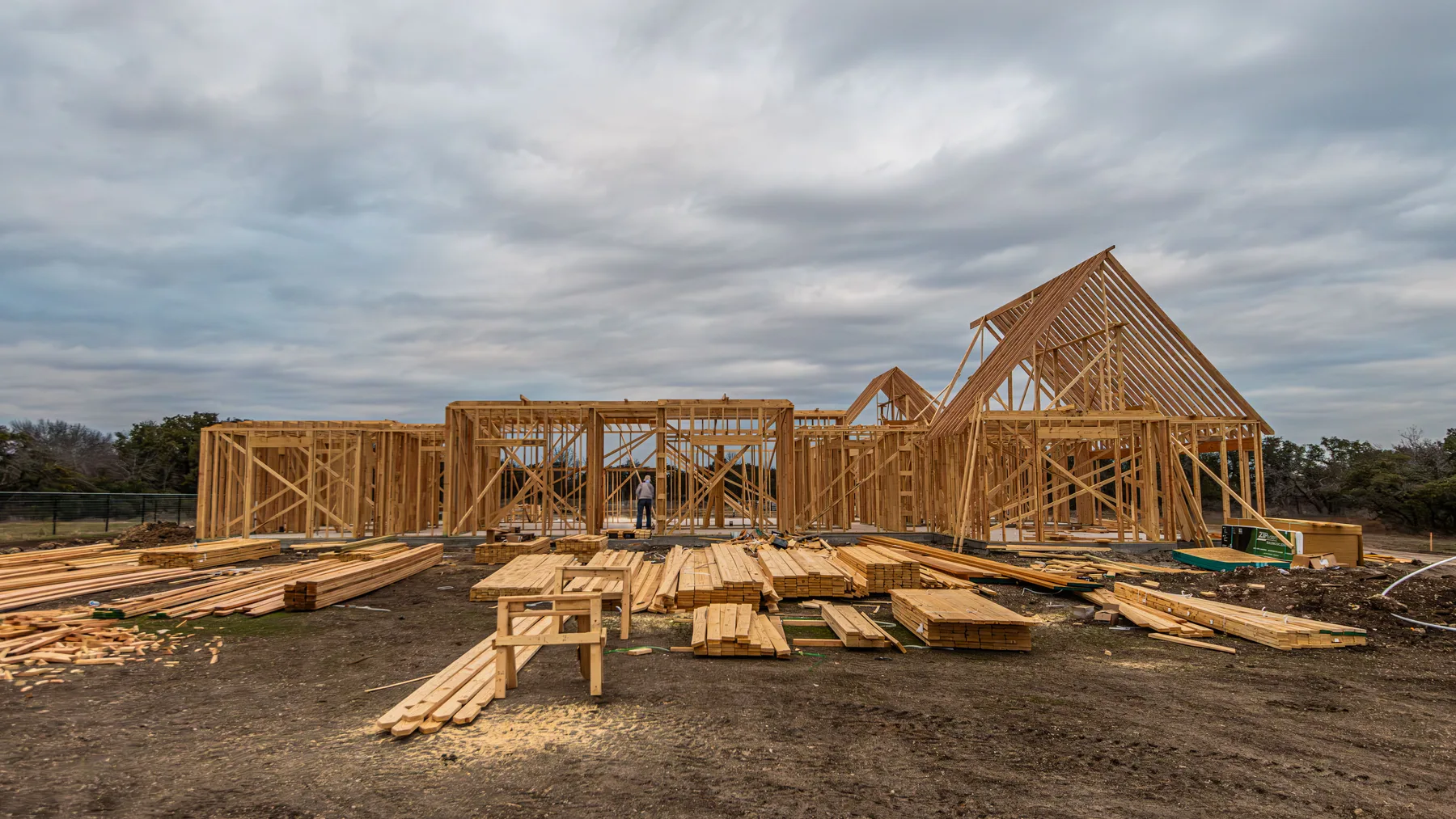 A timber-framed home under construction beneath an open sky; representative construction imagery.
